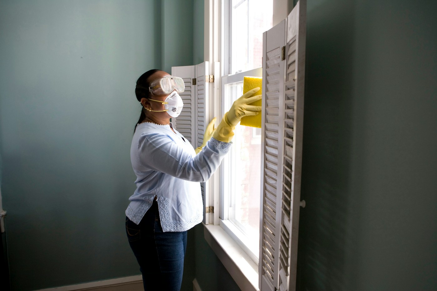 Illustrative photograph of a cleaner wiping an interior window